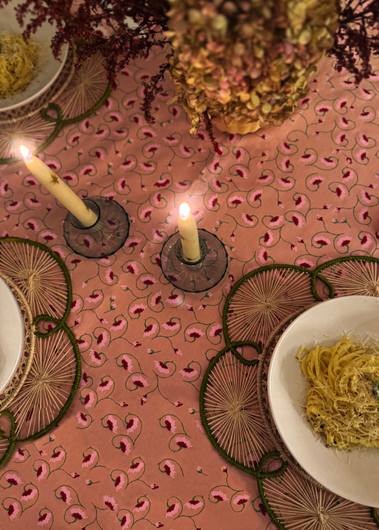 Decorative table setting with candles, plates, and a pink patterned tablecloth.