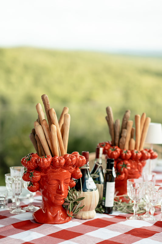 Decorative tuscan setting with a red and white gingham tablecloth with scalloped trim 